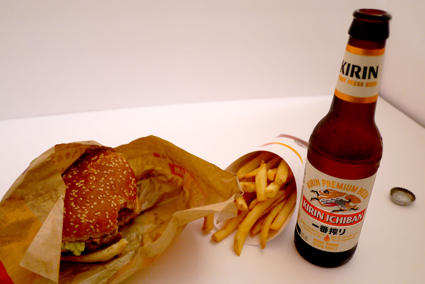 瓶のキリン一番搾りとハンバーガーとフライドポテトの画像