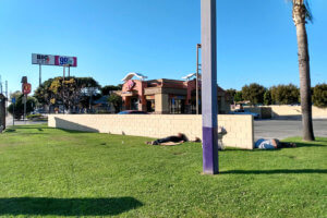 Homeless lies on the grass under blue sky in California