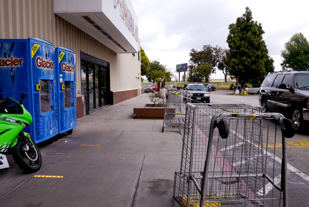 There are shopping carts, cars and motor bike at front of supermarket in LA