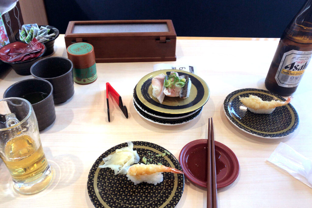 Sushi plates and a bottle of beer on the table at Hama-zushi