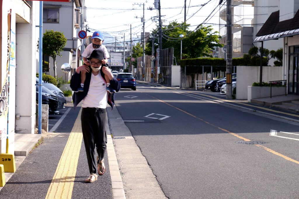 Walking a man on the road his nephew on his shoulders in Hiroshima Japan