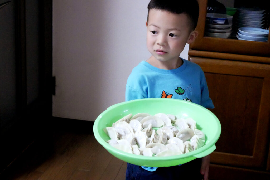 A boy have a lot of gyoza of plate at the Japanese family home