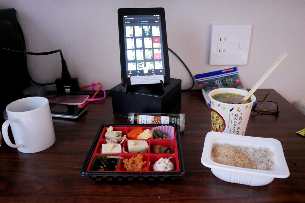 Japanese bento dishes, instant rice, miso soup, tablet kindle fire on the desk at at hotel room in Hiroshima Japan