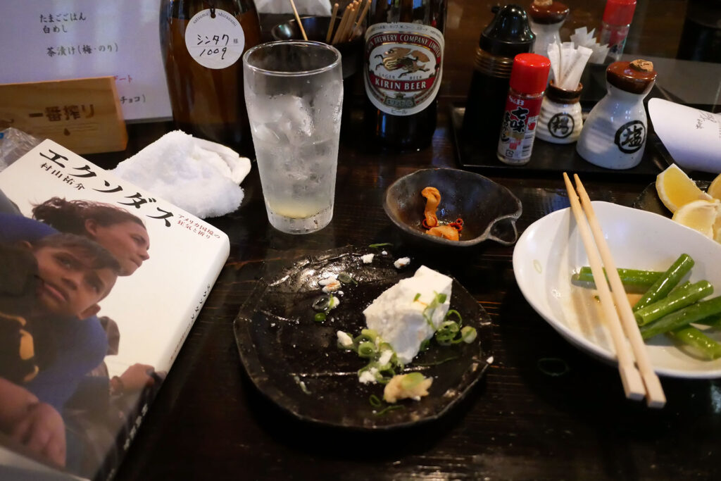 Tofu, soju, chapsticks and a book on the table at izakaya Omasa in Hiroshima Japan