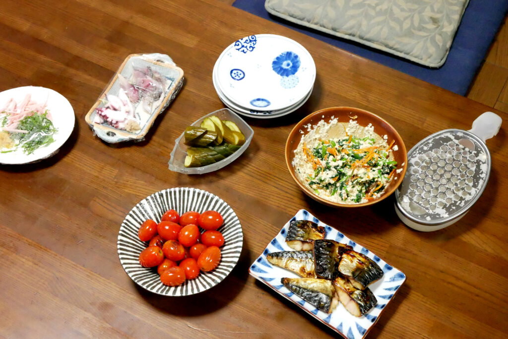 Tomato, grilled mackerel, shiraae, etc Japanese dishes are on the wooden table in Hiroshima Japan