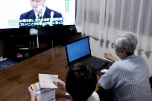 Old parents at the Japanese dining room. A dad is handling laptop to reserve for Covid-19 vaccination.