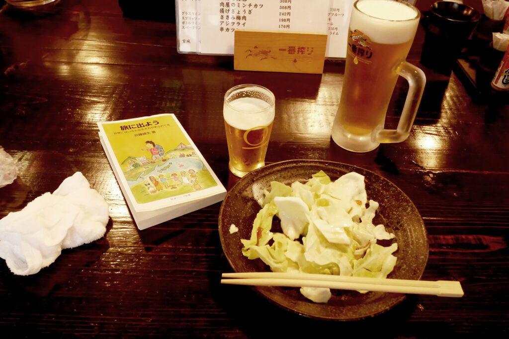 Beer, cabbage, and a book on the table at Japanese Izakaya in Hiroshima Japan
