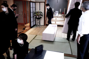 The coffin on the tatami mat floor and people who wore black suits at Japanese funeral