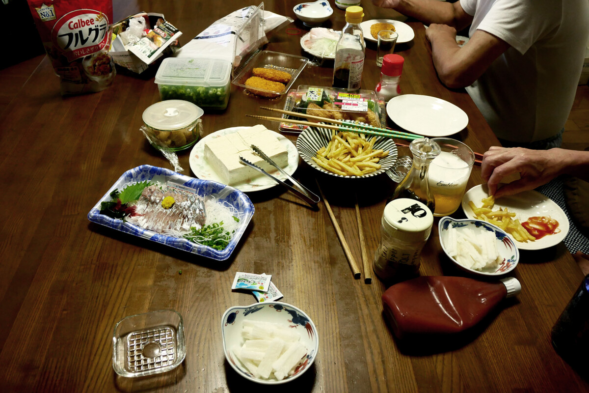 Japanese dinner Japanese dishes like sashimi on the wooden table and people are eating fries