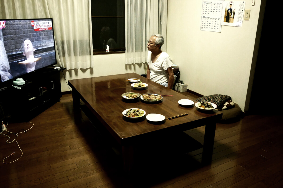 An elder man at the table An elder man who is my father is watching TV at a dining room's table