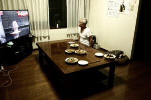 An elder man who is my father is watching TV at a dining room's table