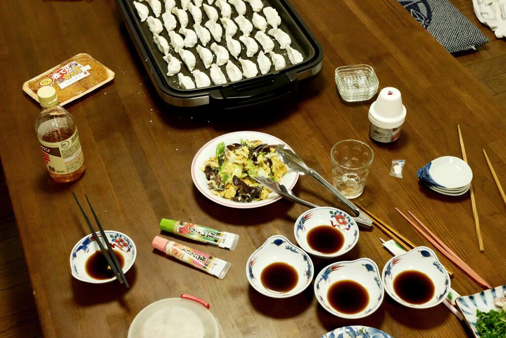 Gyoza on the electric plate, sauce dip, and fried egg on the wooden table