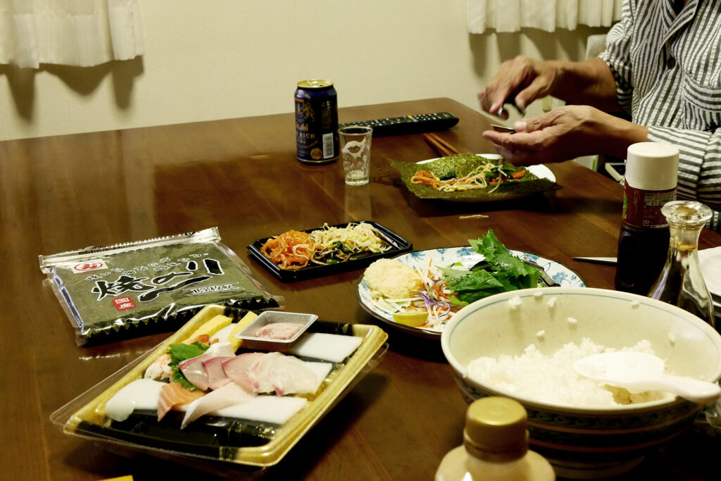 Japanese temaki sushi dishes on the table, an old man who is making sushi