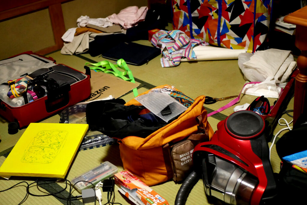 There are canvas, vacuum creaner, a colorful bag on the tatami mat floor