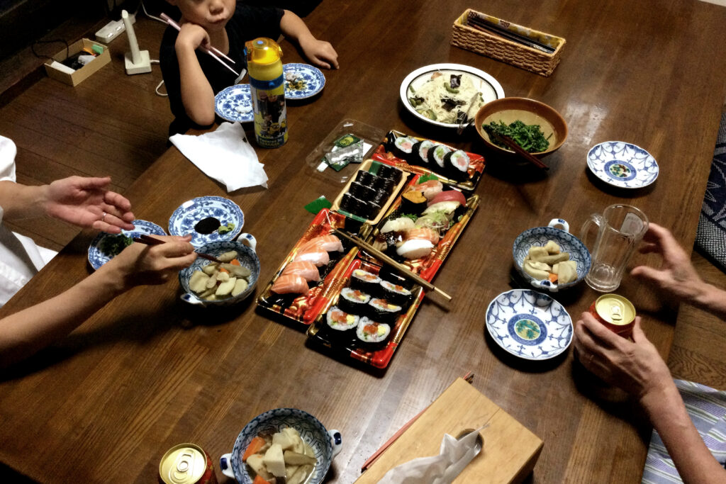 Three people are eating packed sushi on the table