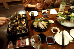 Grilling fresh eel on the fire and sashimi on the table