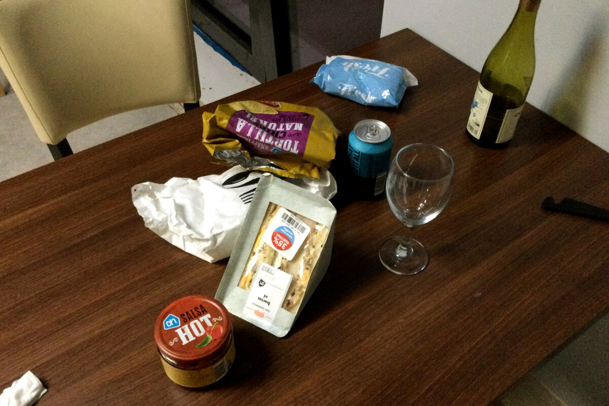 Easy going dinner Sandwiches, a bottle of white wine and glass and salsa sauce on the wooden table in the Netherlands
