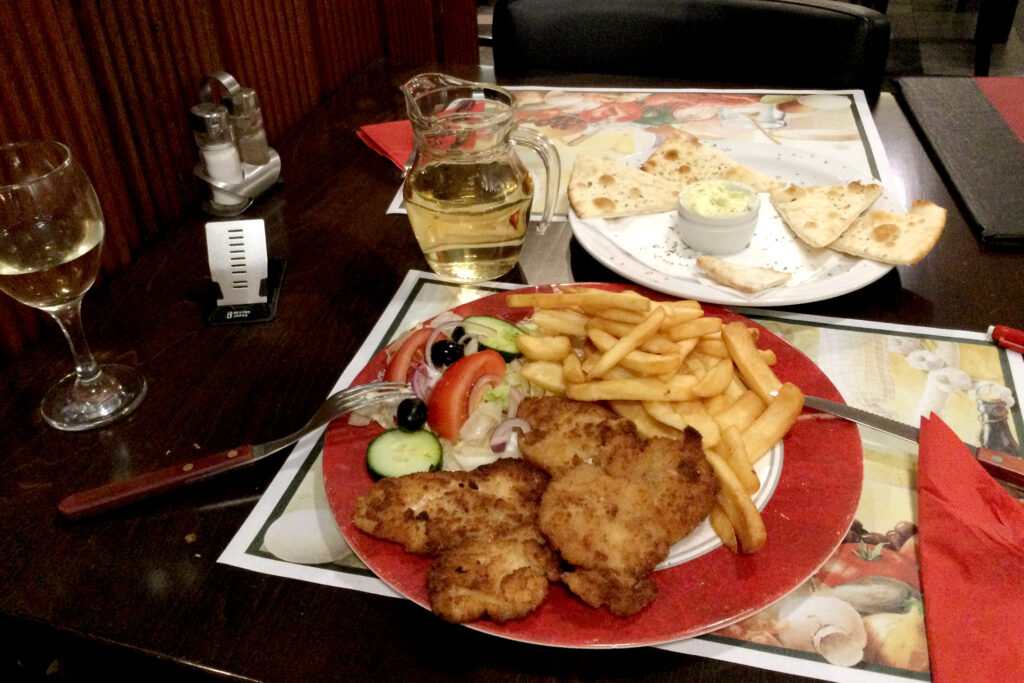 White wine, chicken, fried potatoItalian dinner on the table