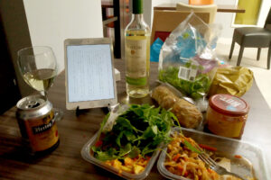 Packed Chinese meals, a bottle of wine, and iPad on the table