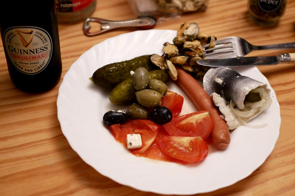 Tomato, olives, sausage and mussel on the plate and a bottle of Guinness beer