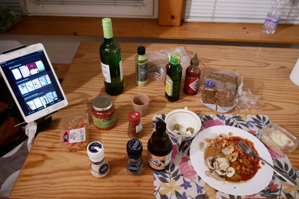 iPad, Beans on the plate, a bottle of white wine and seasoning bottles on the wooden table