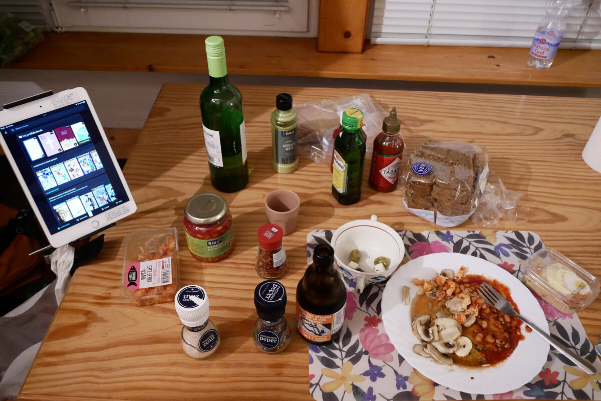 Single life dinner iPad, Beans on the plate, a bottle of white wine and seasoning bottles on the wooden table