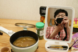 A man photo shooting mirror, there is hot pot on the table