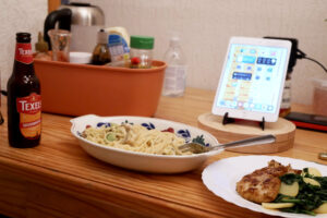 Beer, pasta, iPad and pork steak plate on the wooden table