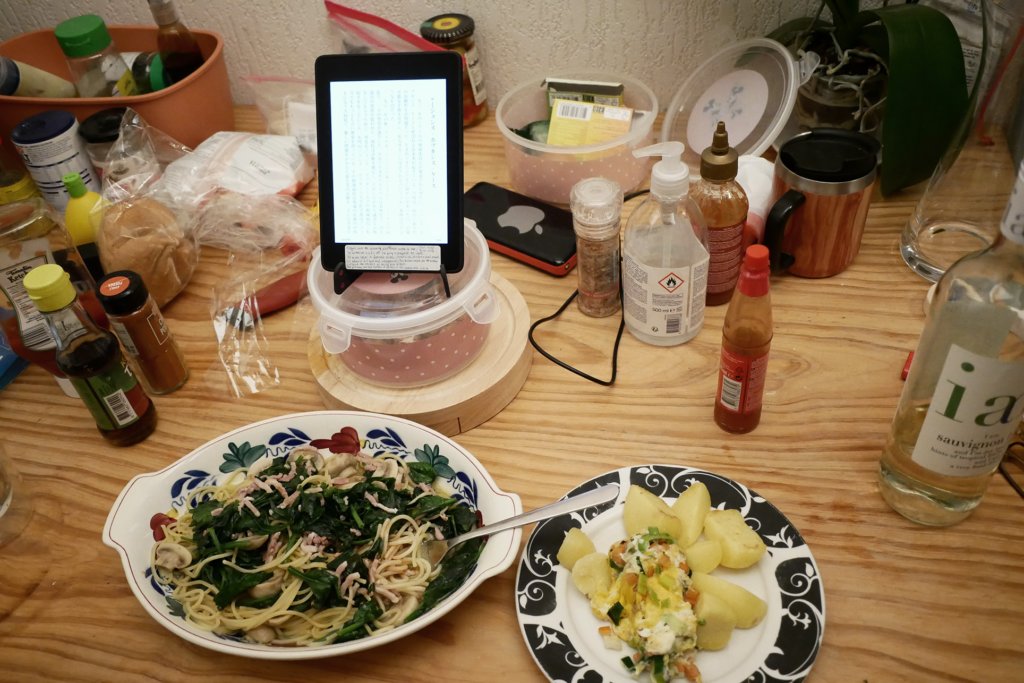 Spaghetti, potato, and fried egg on the plate, Kindle book on the wooden table