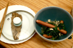 A fillet of mackerel and sausage with spinach on the wooden table