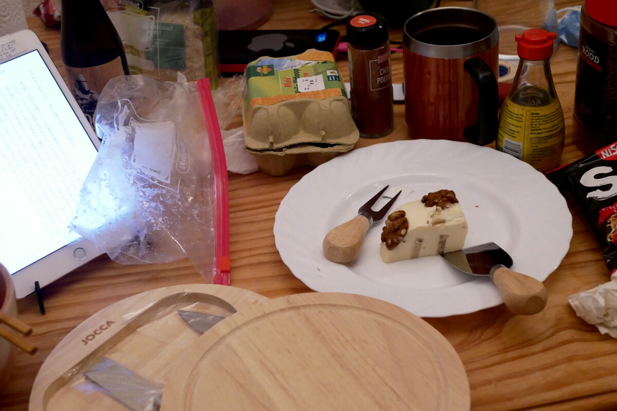 Messy wooden table, there are iPad, cheese, and knives