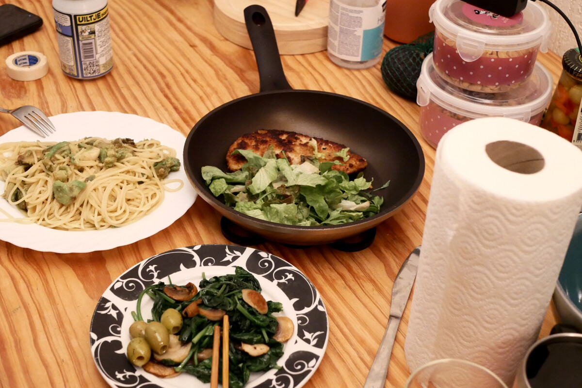 Pasta, spinach, and pork steak dinner, paper towel roll on the wooden table