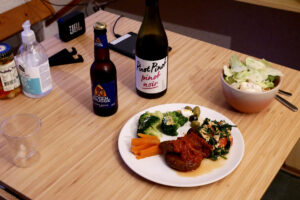 A bottle of Beer and red wine, hamburger plate on the wooden table for single man dinner