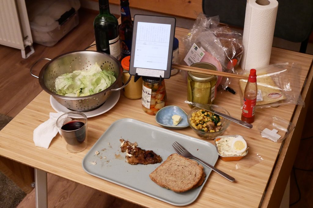 Single man light dinner, like sandwiches, red wine, etc., on the wooden table
