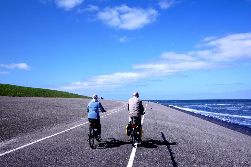 blue sky, blue ocean, there are two elder Dutch cyclist in Den Helder