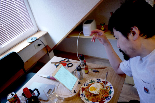 Middle age Japanese man eating spaghetti in the small room in the Netherlands