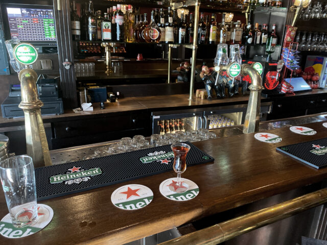 At bar counter, there are empty glass and liquor of the small glass