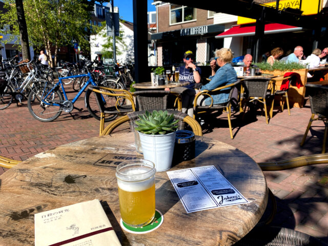 at outside seat of the bar, beer and book on the table