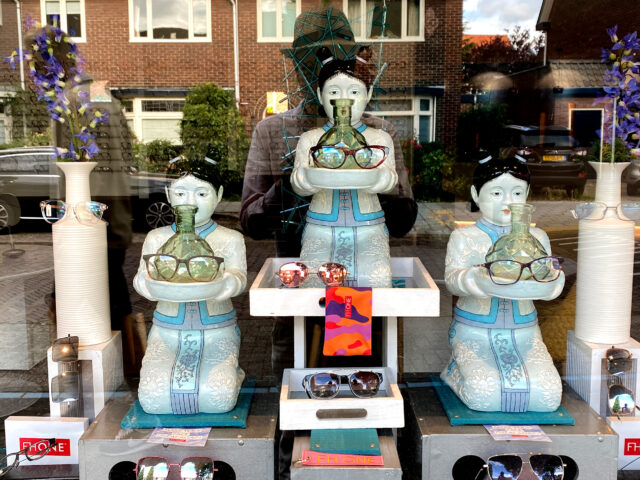 Pottery Asian doll has glasses on the show window in the Netherlands