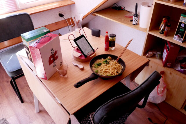 Spaghetti on the pan, wine boxes, kindle on the wooden table