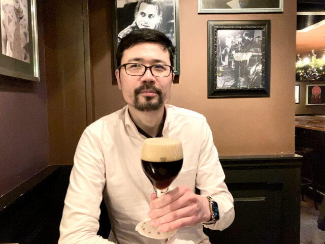 an asian man drinking beer at the bar